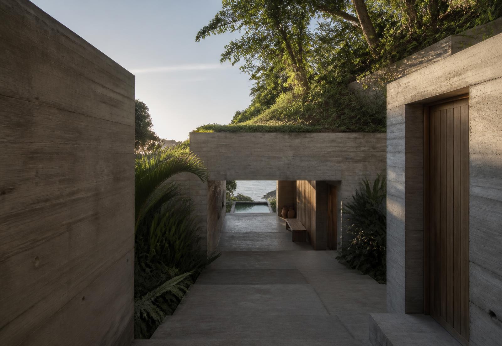 Sichtbetonhaus mit schmalem Eingang und Pool, in den Hang gebaut